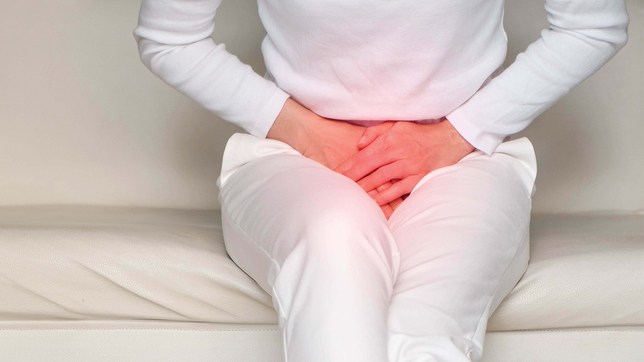 A woman wearing white jeans is pissing in the public toilet